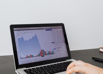 A person looking at a laptop displaying cryptocurrency graphs and AI algorithms.
