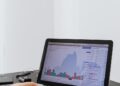 A person analyzing Bitcoin energy consumption data on a laptop with graphs and charts.
