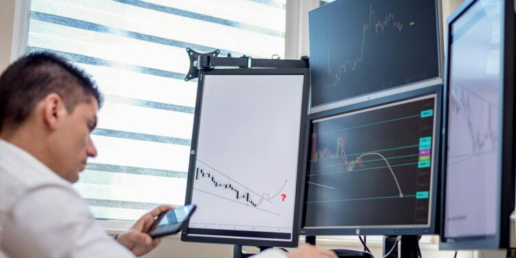 Traders analyzing stock charts with digital screens showcasing tokenized stocks and ETFs.