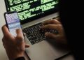 Laptop with cryptocurrency symbols and hacking code on the screen, highlighting cyber theft.