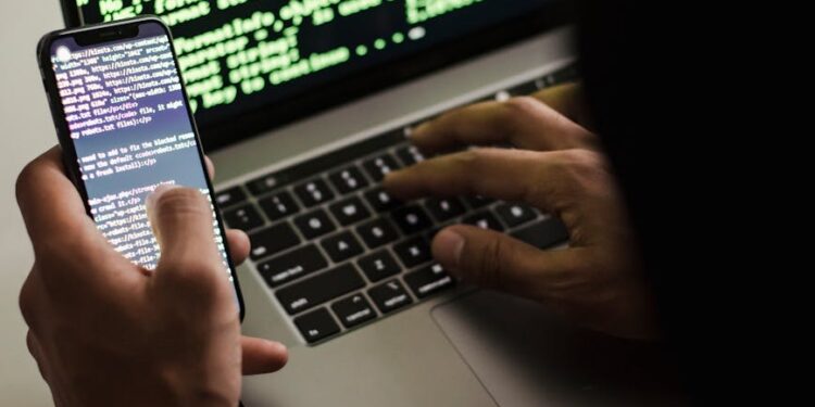 Laptop with cryptocurrency symbols and hacking code on the screen, highlighting cyber theft.