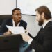 Two professionals discussing crypto payment solutions at a conference table with charts and laptops.