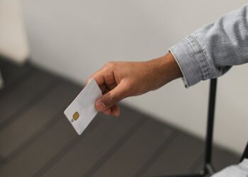 Hand holding a sleek corporate card with a digital interface showcasing financial data.